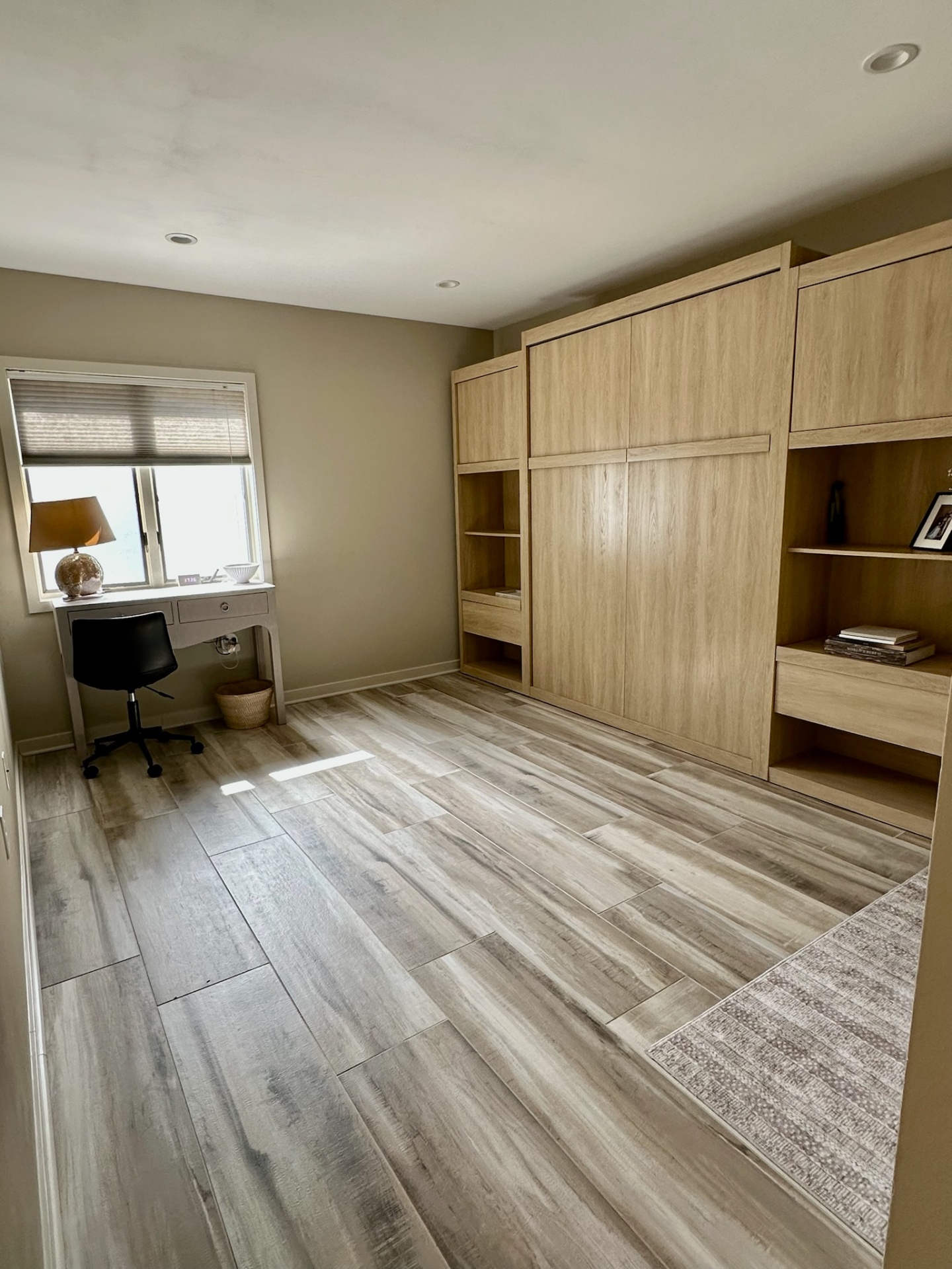Den with Murphy bed cabinetry, desk, and sunlit window