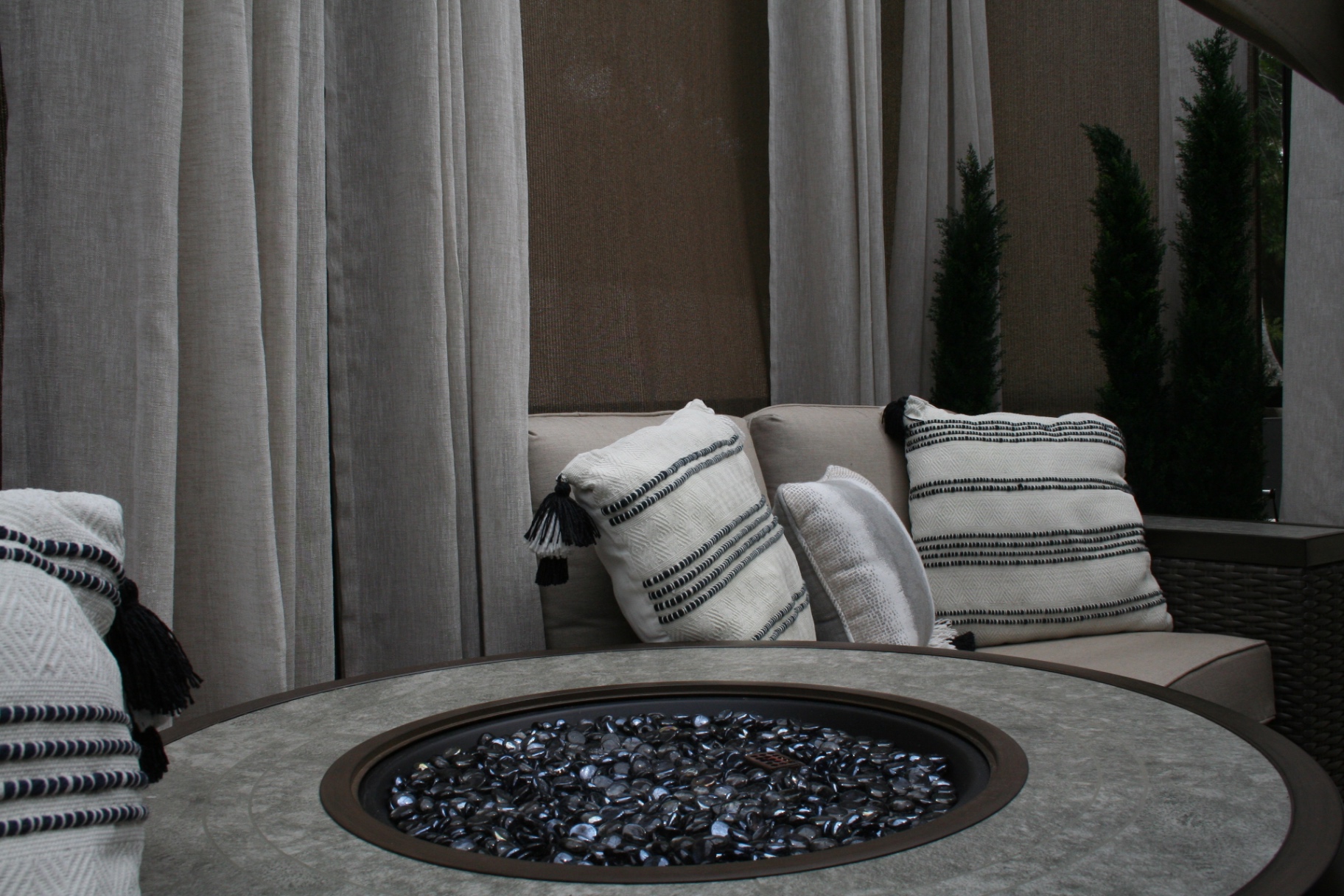 Round fire pit table with black glass beads and cushioned seating