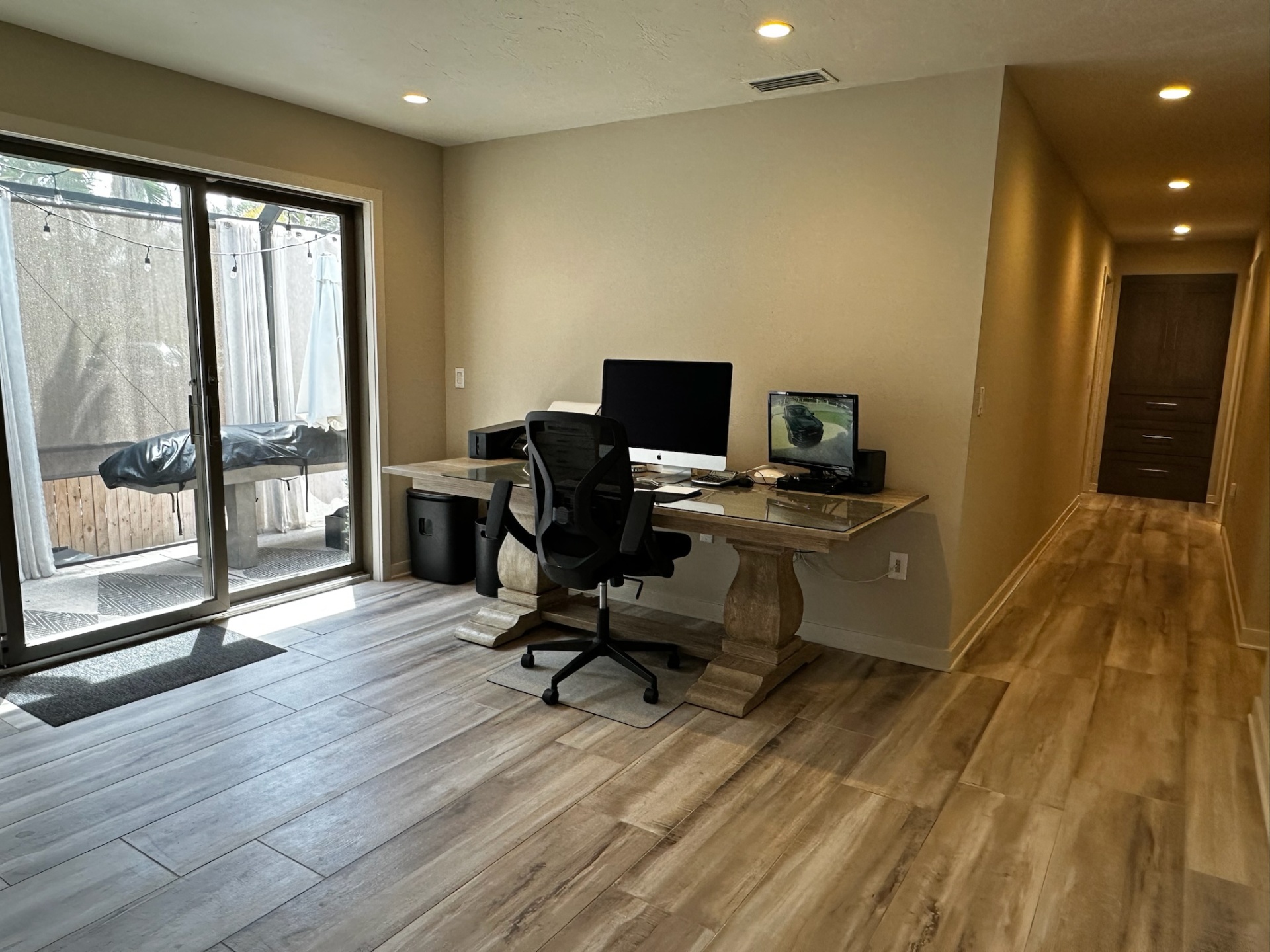 Office with sliders to the patio and long hallway view