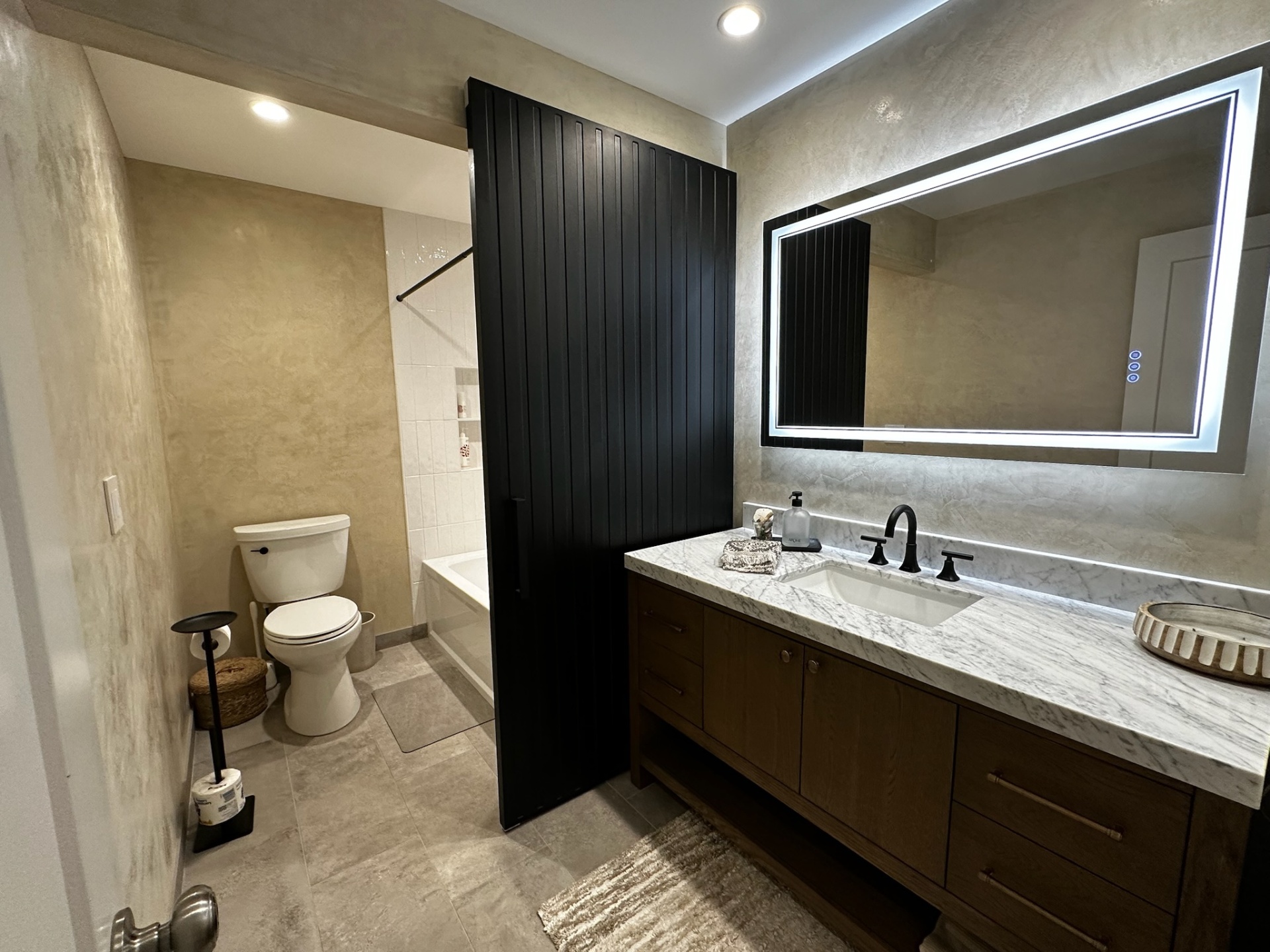 Guest bath with marble vanity, LED mirror, and black barn door