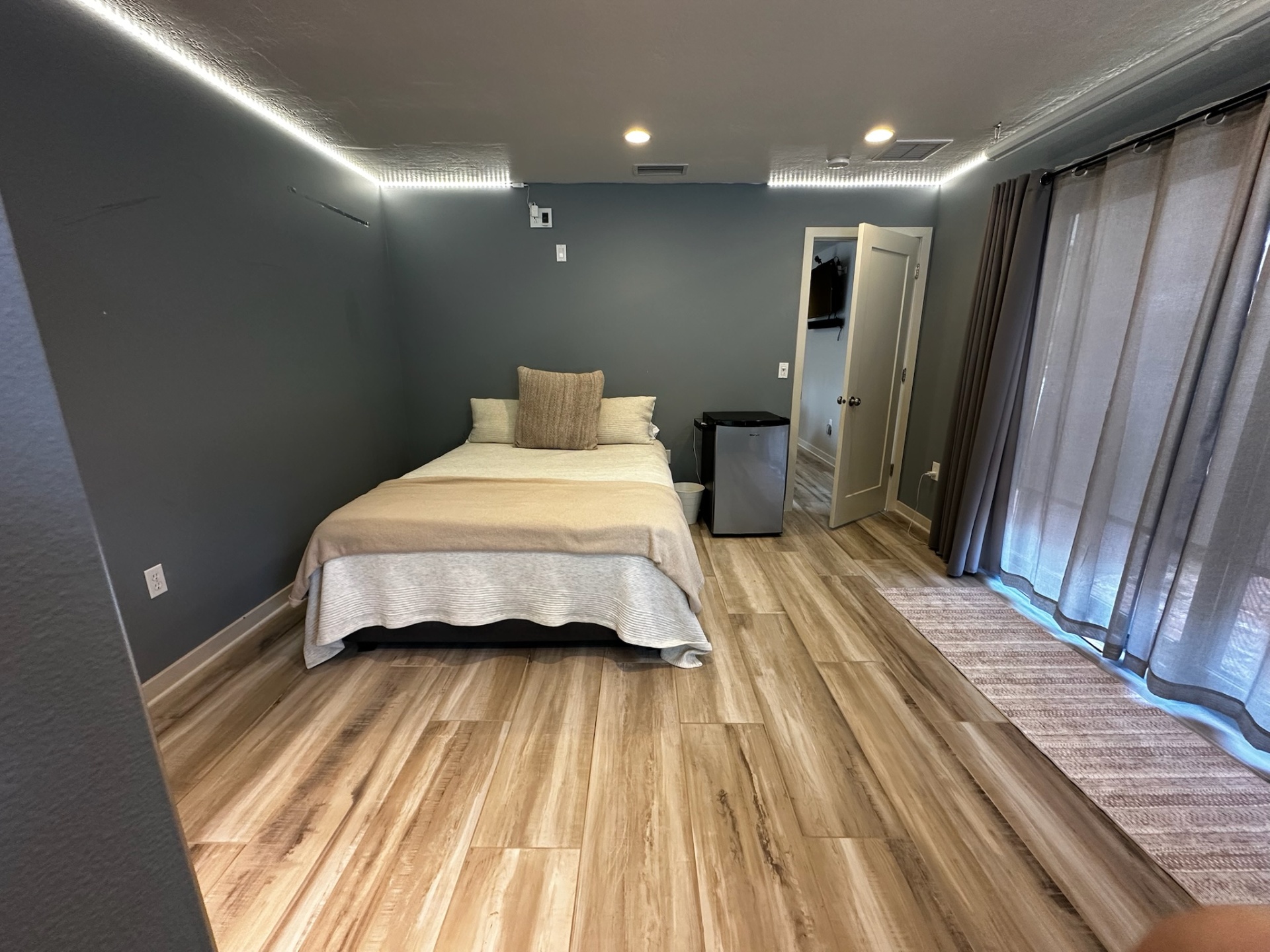 Guest bedroom with queen bed, cove lighting, and sliders to the patio