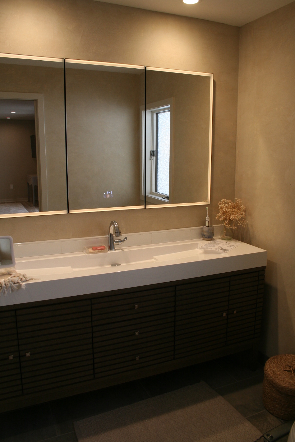 Primary bath floating vanity with backlit tri-mirror cabinet and Venetian plaster walls