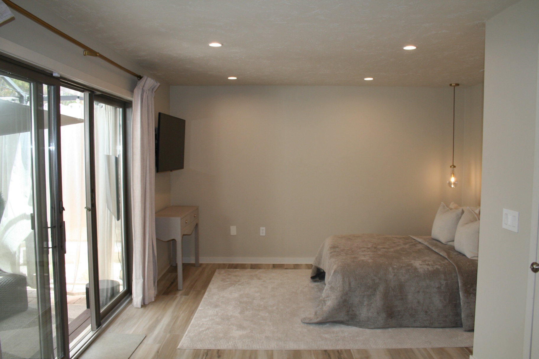 Primary bedroom wide view with king bed and sliders to the patio